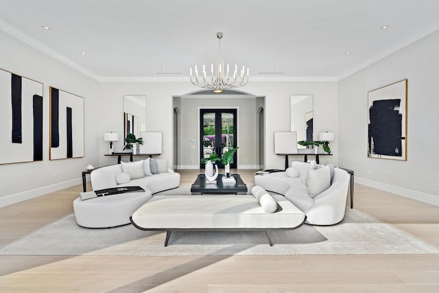 living room with an inviting chandelier, french doors, light wood-type flooring, and crown molding