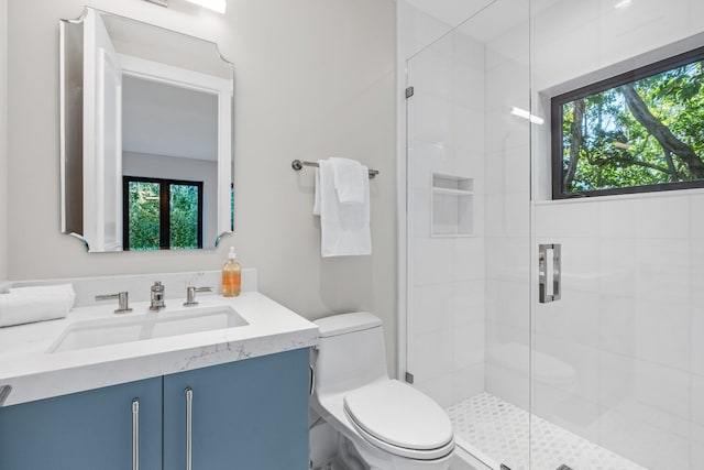 bathroom featuring a shower with shower door, toilet, and vanity