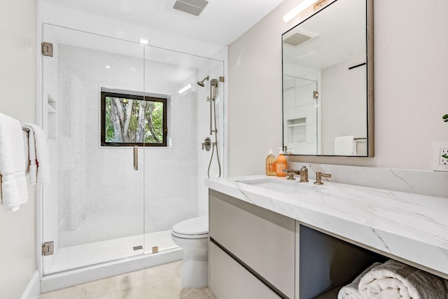 bathroom with tile floors, a shower with door, large vanity, and toilet