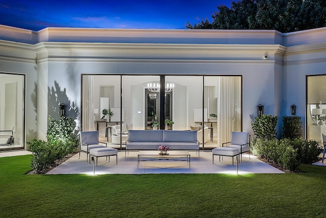 back house at dusk with outdoor lounge area, a patio area, and a lawn