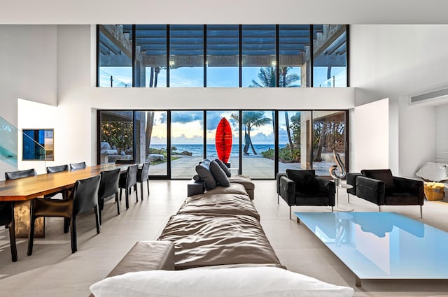 living room with a water view, a towering ceiling, and light tile patterned floors