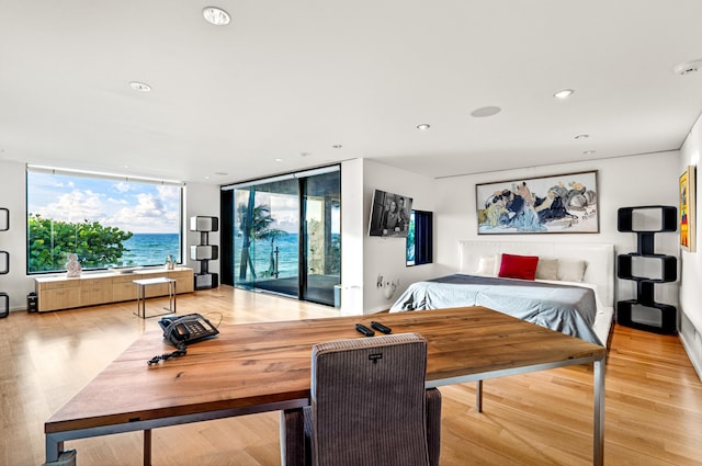 bedroom featuring expansive windows, light hardwood / wood-style flooring, and access to outside