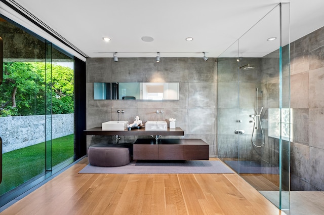 bathroom with hardwood / wood-style flooring, vanity, track lighting, and a shower with shower door