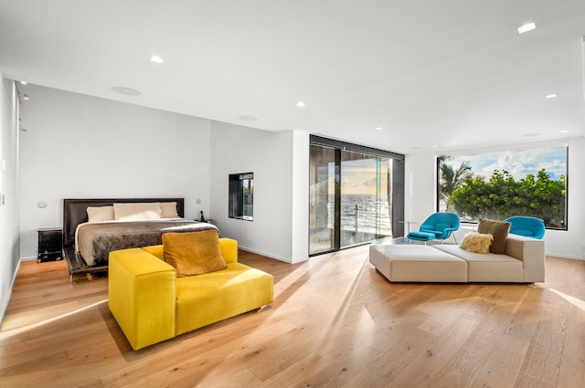 bedroom with a wall of windows, light hardwood / wood-style floors, and access to outside