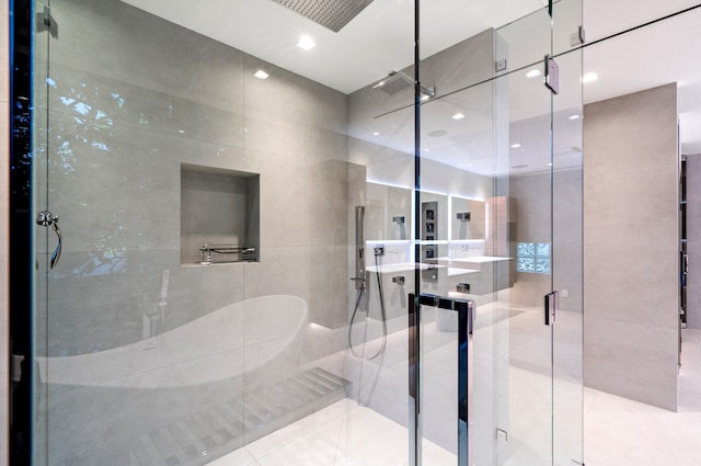 bathroom featuring tile patterned flooring, a shower with door, and tile walls