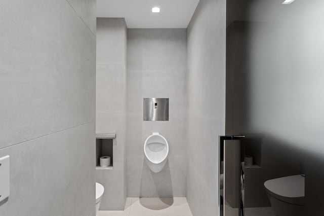 bathroom with tile patterned floors, toilet, and tile walls