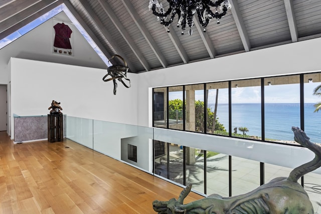 interior space with a water view, high vaulted ceiling, wooden ceiling, hardwood / wood-style flooring, and beam ceiling