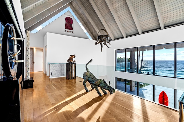 interior space with high vaulted ceiling, light hardwood / wood-style floors, beamed ceiling, and a water view