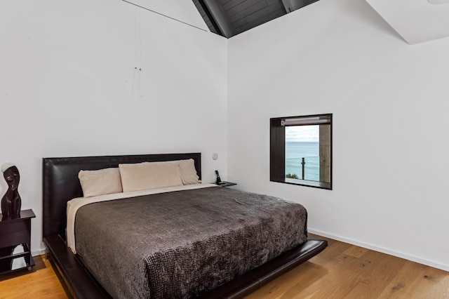 bedroom with light hardwood / wood-style flooring and high vaulted ceiling