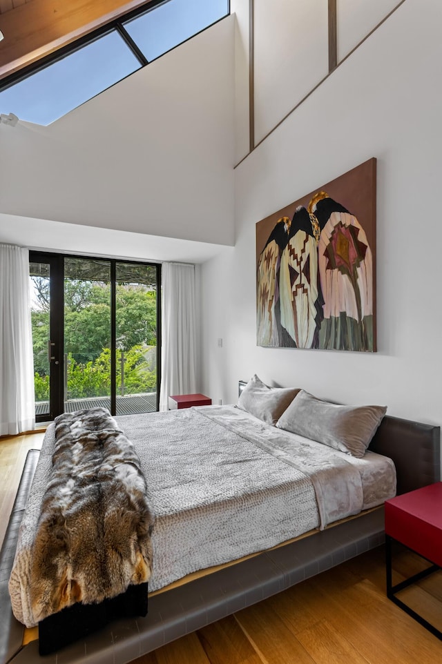 bedroom with hardwood / wood-style flooring and a towering ceiling