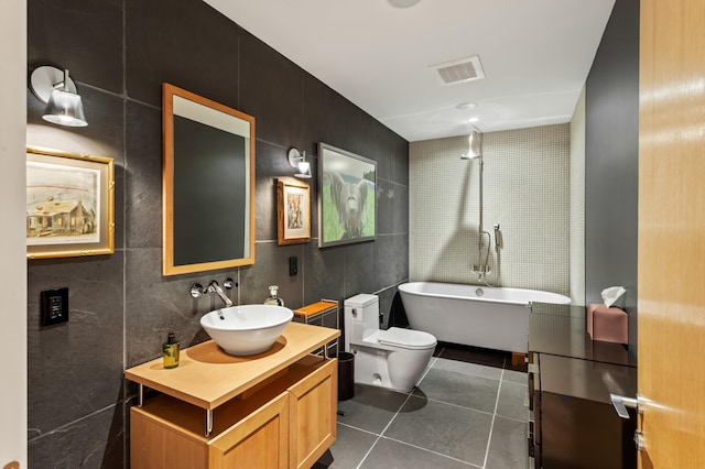 bathroom featuring tile patterned floors, toilet, tile walls, vanity, and a bathtub