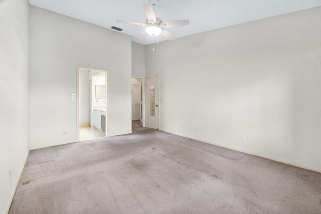 spare room with a high ceiling, light colored carpet, and ceiling fan