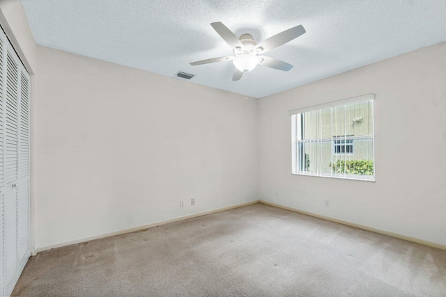 carpeted spare room featuring ceiling fan and a textured ceiling