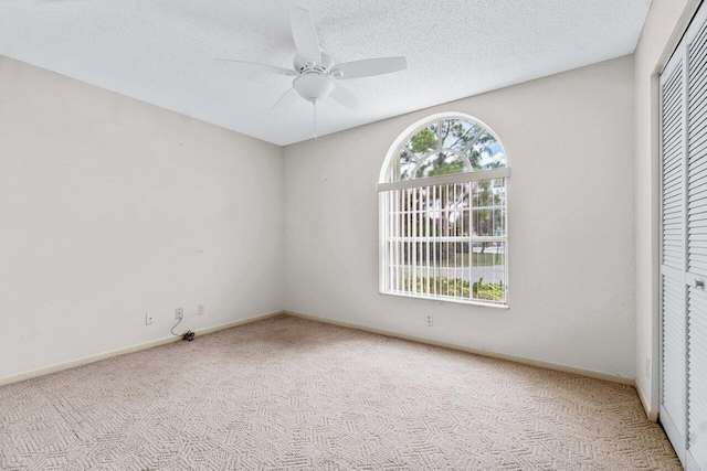 unfurnished bedroom featuring ceiling fan, multiple windows, light carpet, and a closet