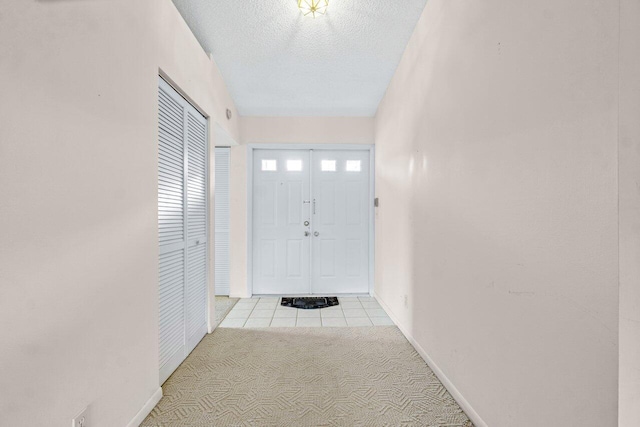 entryway with light carpet and a textured ceiling