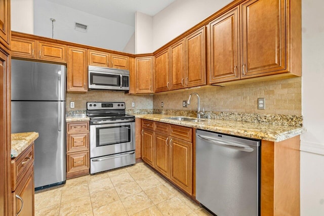 kitchen featuring backsplash, stainless steel appliances, light stone counters, and sink