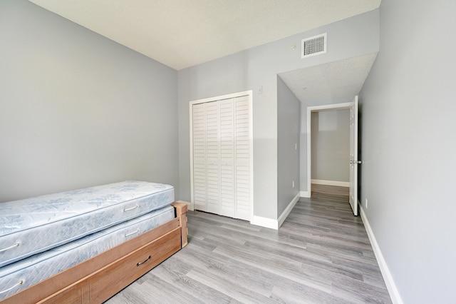 bedroom featuring a closet, a textured ceiling, and light wood-type flooring