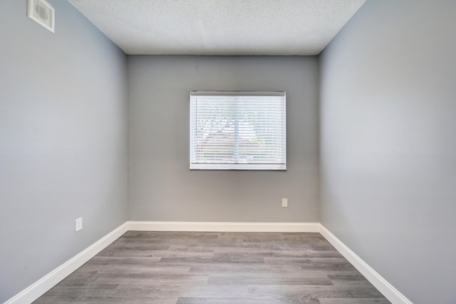 spare room featuring light hardwood / wood-style floors and a textured ceiling