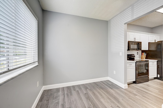 kitchen with electric range, white cabinets, light hardwood / wood-style floors, and a textured ceiling