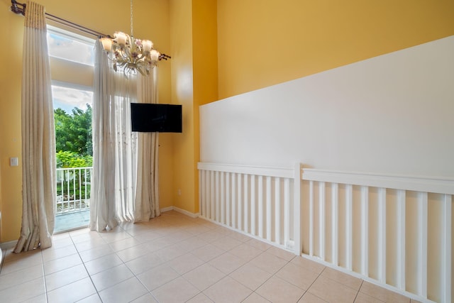 unfurnished room with an inviting chandelier, a healthy amount of sunlight, and light tile patterned floors