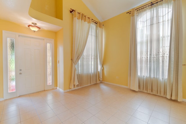 foyer featuring vaulted ceiling, light tile patterned floors, and plenty of natural light