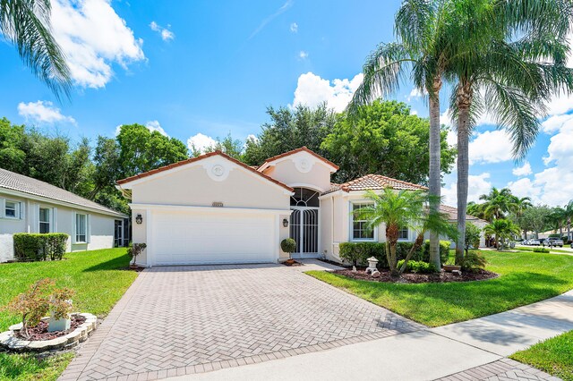 mediterranean / spanish-style house featuring a garage and a front lawn