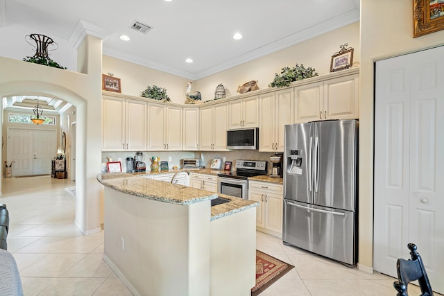 kitchen featuring crown molding, light tile patterned floors, stainless steel appliances, light stone countertops, and cream cabinets