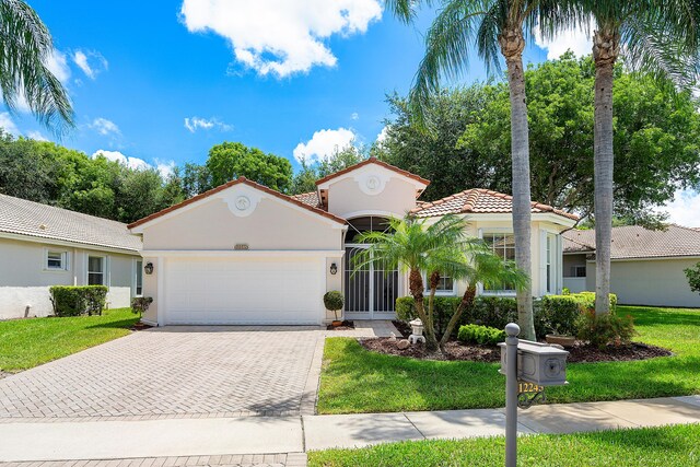 mediterranean / spanish house with a garage and a front lawn