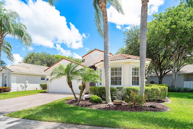 mediterranean / spanish house with a garage and a front lawn