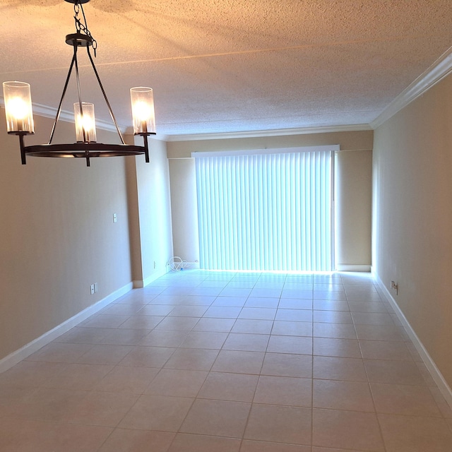 tiled empty room with a textured ceiling, an inviting chandelier, and ornamental molding