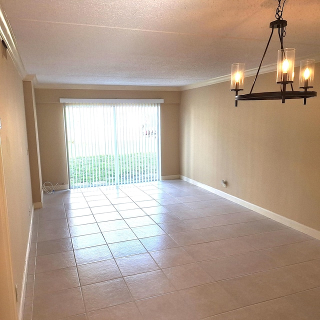 empty room with light tile patterned floors, ornamental molding, and an inviting chandelier