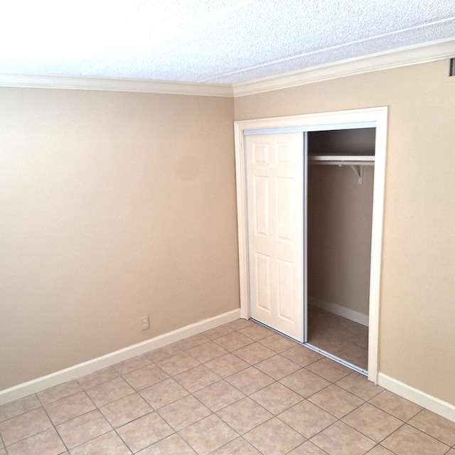 unfurnished bedroom with ornamental molding, light tile patterned floors, and a closet