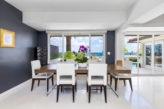 dining space featuring a water view and concrete flooring