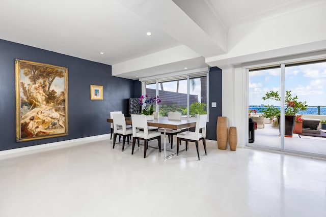 dining room with concrete flooring and a water view