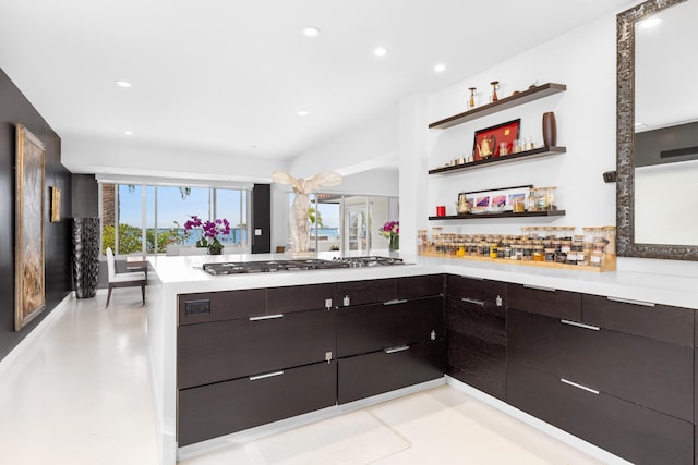 kitchen featuring tasteful backsplash, stainless steel gas stovetop, kitchen peninsula, and dark brown cabinets