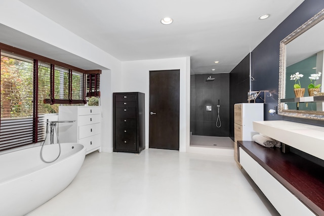 bathroom featuring concrete floors, independent shower and bath, and vanity