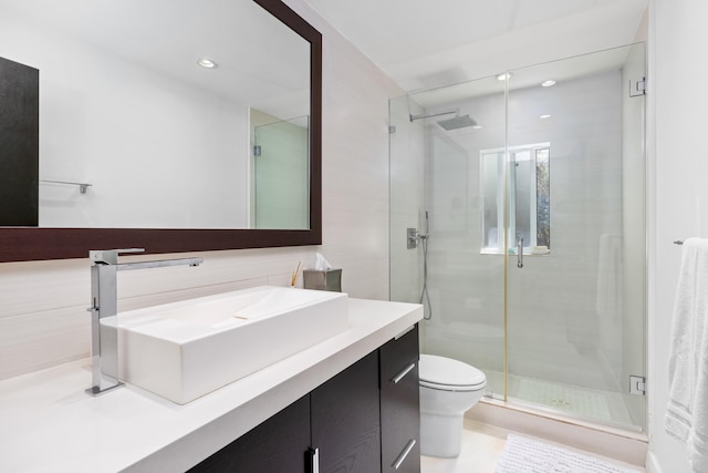 bathroom featuring walk in shower, vanity, toilet, and tile walls