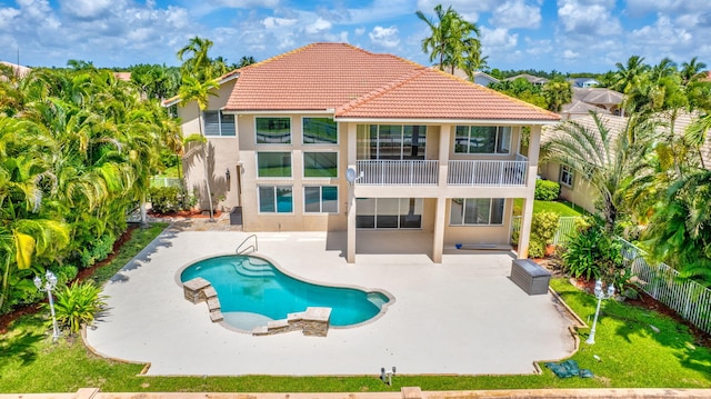 rear view of property featuring a fenced in pool and a patio area