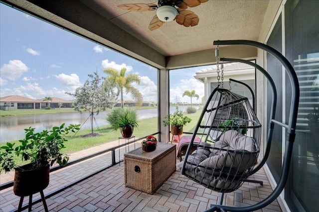 sunroom / solarium with a water view and ceiling fan