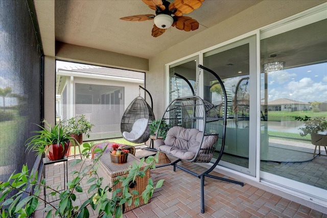 sunroom / solarium with a wealth of natural light, a water view, and ceiling fan