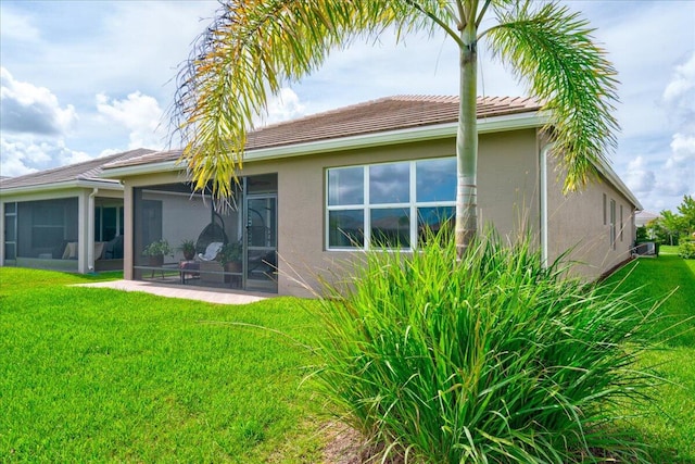 rear view of property with a sunroom, a lawn, and a patio area