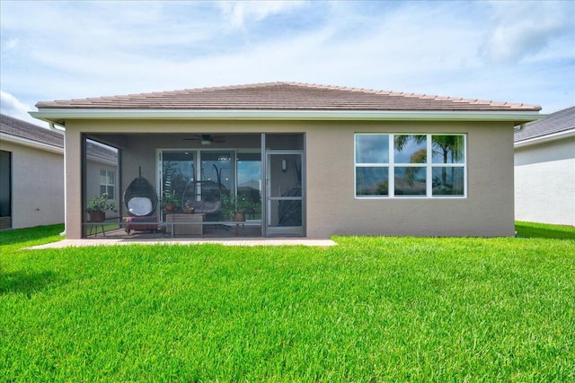 rear view of house with a sunroom, a lawn, and ceiling fan