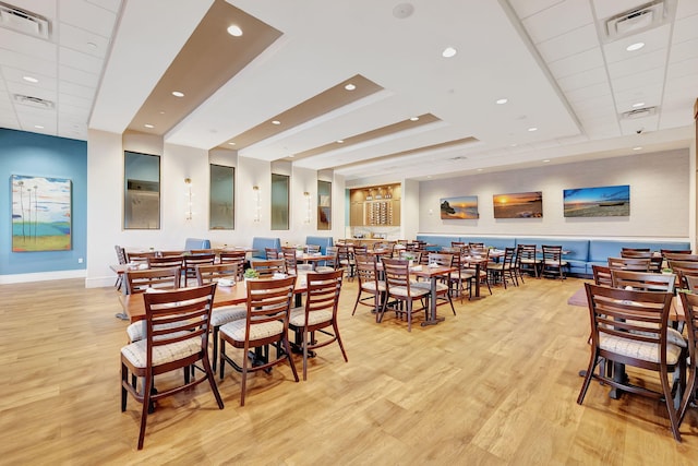 dining space featuring a tray ceiling and light wood-type flooring