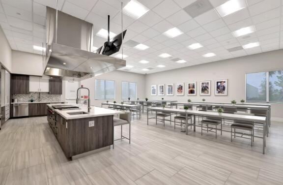 kitchen with sink, a drop ceiling, a kitchen bar, dark brown cabinetry, and a center island with sink