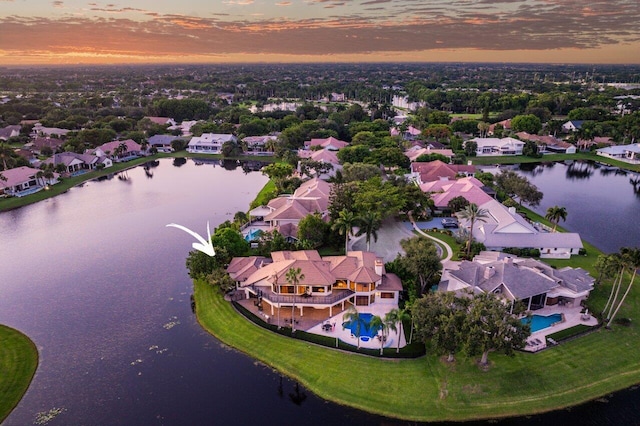 aerial view at dusk with a water view and a residential view