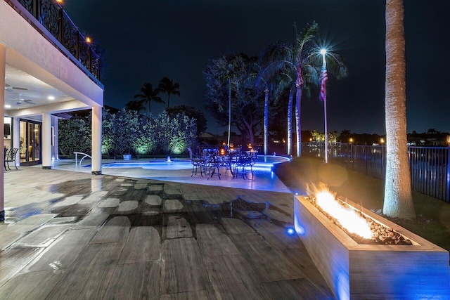 pool at twilight featuring a patio area, an outdoor fire pit, an outdoor pool, and ceiling fan