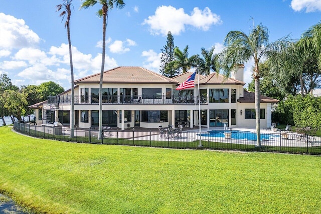 rear view of house featuring a fenced in pool, a balcony, fence, a yard, and a patio area