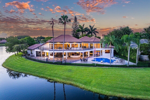 back of property with a patio, a water view, fence, and a balcony