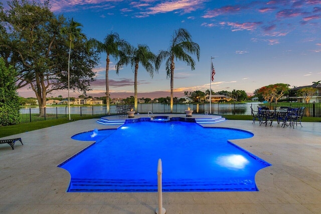 pool at dusk featuring pool water feature and a patio area