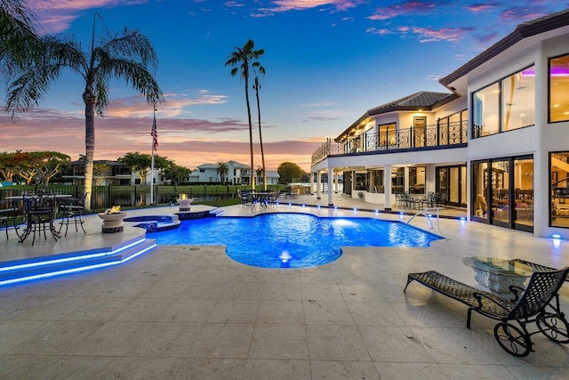 view of swimming pool featuring a pool with connected hot tub, fence, and a patio